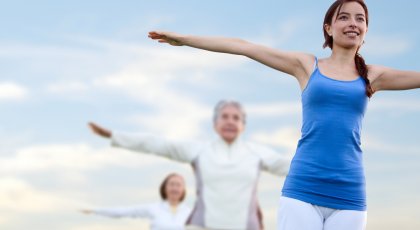 Women practicing yoga together, in Mountain Pose (Tadasana) with arms wide