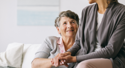 older woman with alzheimer's disease holding her daughter's hand. 