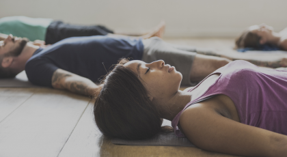 Yoga class practicing for stress relief in Corpse Pose (Savasana)