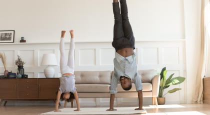 A man and his child practicing yoga Handstand Pose