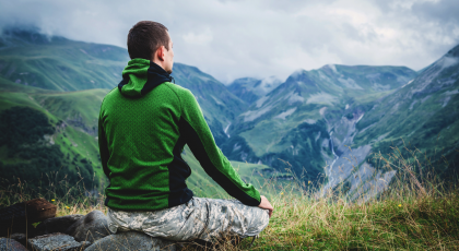 veteran yoga man meditating outside in mountains