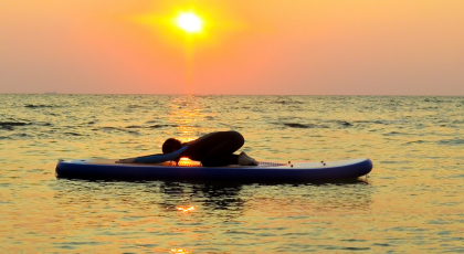 A yoga practitioner practicing Child's Pose (Balasana) on a kayak to benefit of self-awareness