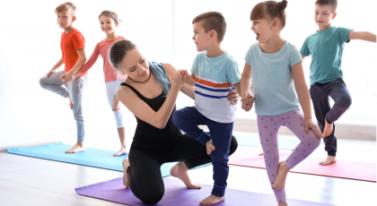 Yoga class for kids in school practicing Tree Pose (Vrkasana)
