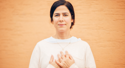 yoga woman standing calm with hands over heart in self-acceptance