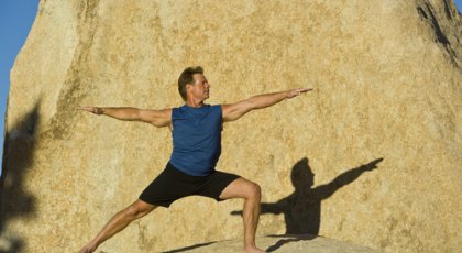 Man practicing yoga asanas, Warrior II pose (Virabhadrasana II), that can help lower high blood pressure naturally.