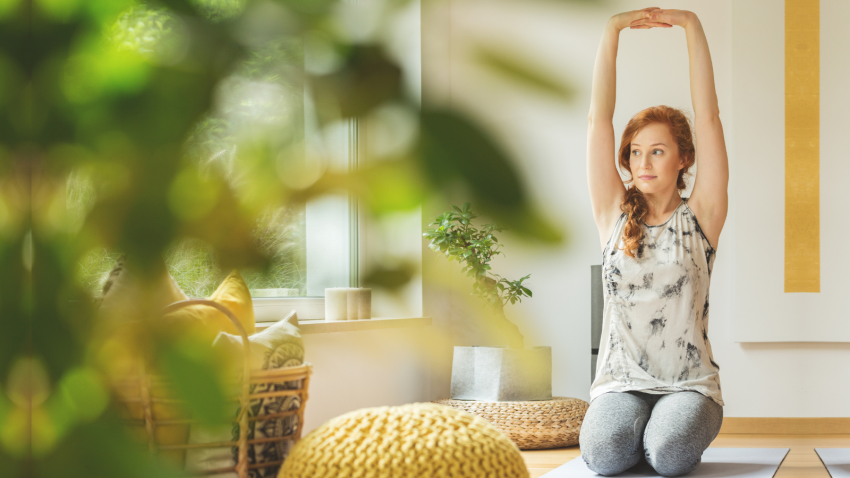 Young woman with hands clasped in Arms Overhead Pose or Urdhva Hastasana Pose.