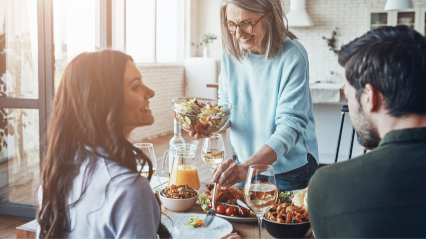 Gathering for the Holidays and enjoying food and family. Happy family enjoying delicious dinner and smiling while sitting in the modern apartment