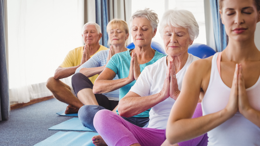 Group of older yoga students practicing to help the symptoms of rheumatoid arthritis