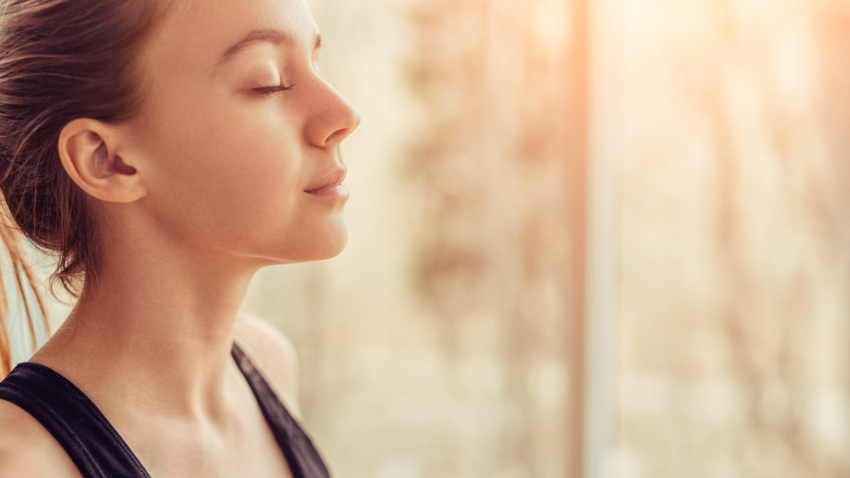 Side view offemale yoga student with closed eyes breathing while doing a breath practice during yoga