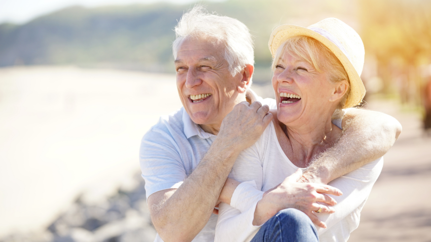 Senior couple relaxing by the sea on sunny day. 