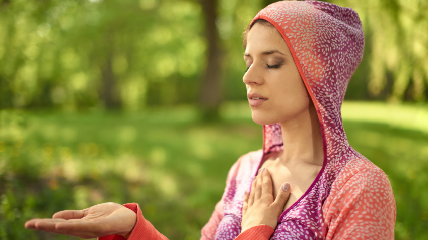 How to cultivate yogic wisdom. Portrait of beautiful woman meditating and doing yoga at sunset on the grass in a park or forest