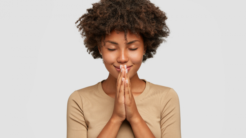 How to maintain a sense of inner peace in the midst of change Beautiful young black woman stands in meditative pose, holds hands in Anjali Mudra