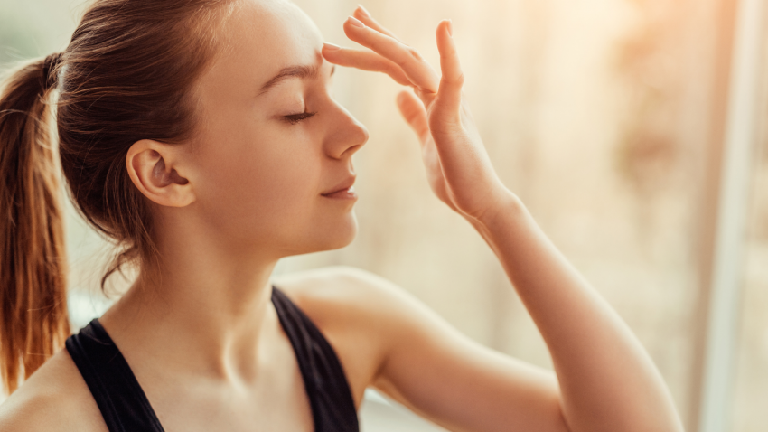 How to practice Ajna Chakra (Chakra of higher perception) Side view of beautiful young female with closed eyes touching Ajna chakra on her forehead