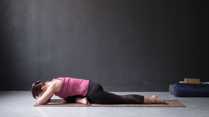 How to practice Pigeon Pose version without props-although props are included in the image. woman resting in forward folded One Legged King Pigeon Pose.