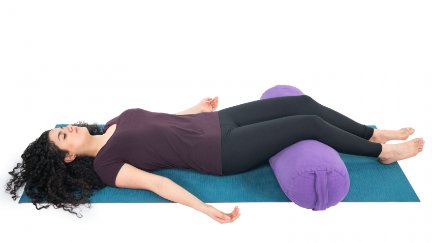 How to practice Restorative Yoga to experience the relaxation response Restorative Savasana with a bolster to support the legs