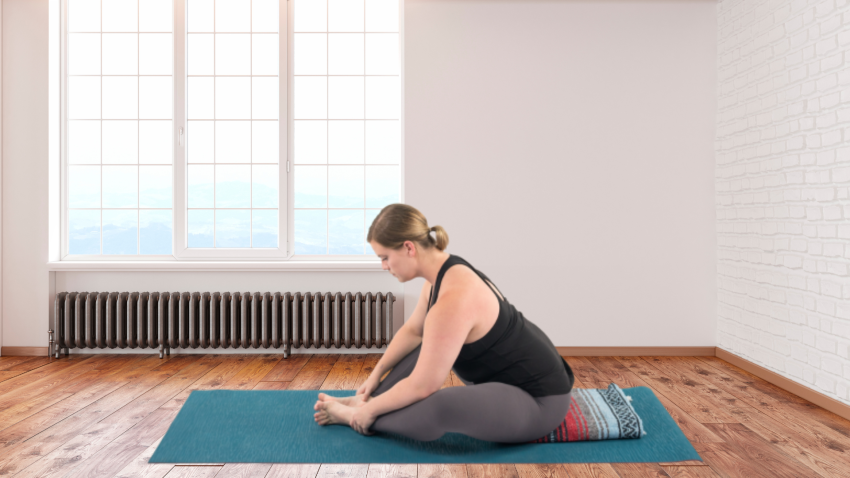 Image depicts a forward fold in Cobbler's Pose or Baddha Konasana.