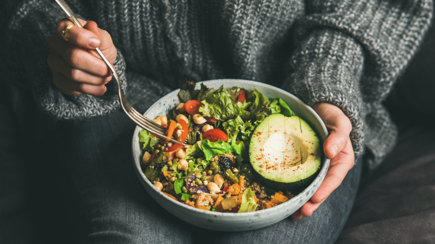 Superfood, clean eating, diet for improving fiber and overall health woman having a healthy vegetarian dinner of fresh salad, avocado, grains, beans, roasted vegetables