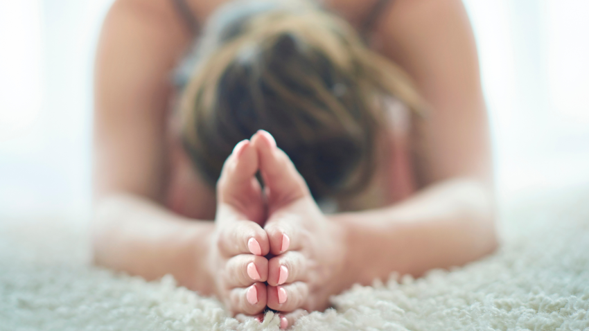 Yin Yoga depicted in this image with woman practicing a forward bend.