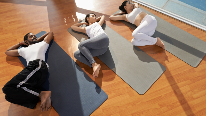 Yoga students practicing Supine Spinal Twist Pose (Supta Matsyendrasana) for happy and healthy hips