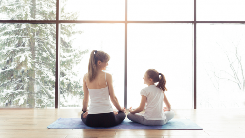 Woman and daughter meditating in front of winter window. Woman and daughter meditating in front of winter window.