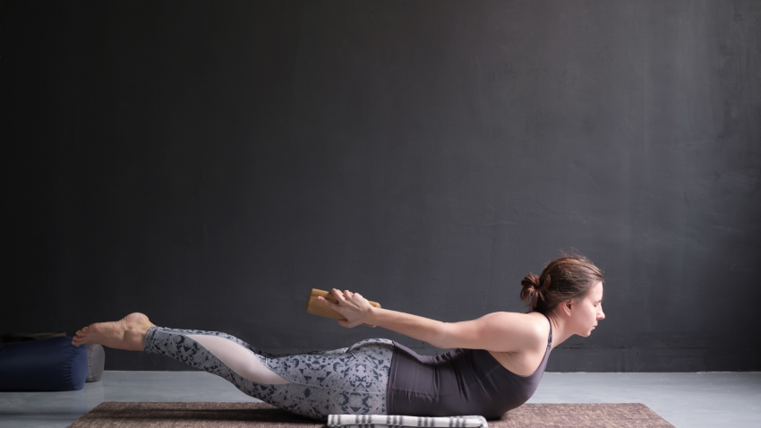 Woman practicing yoga salabhasana locust pose.