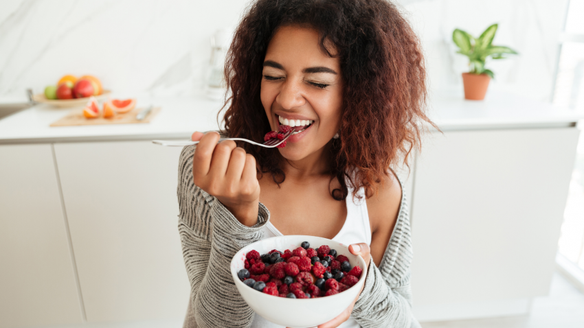 Woman eating bowl of raspberries. Woman eating bowl of raspberries.