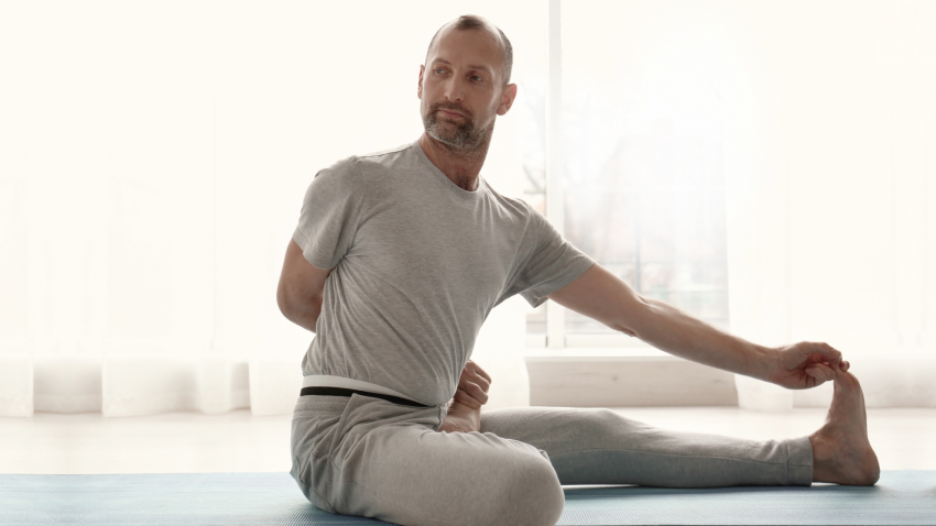 Man practicing yoga forward bend - janu sirsasana. Man practicing yoga forward bend - janu sirsasana.
