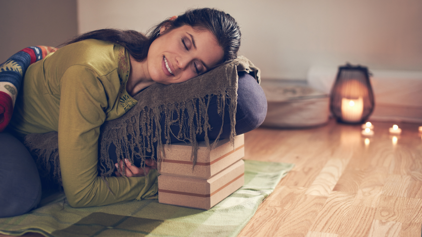 Woman practicing restorative yoga twist on a bolster. Woman practicing restorative yoga twist on a bolster.