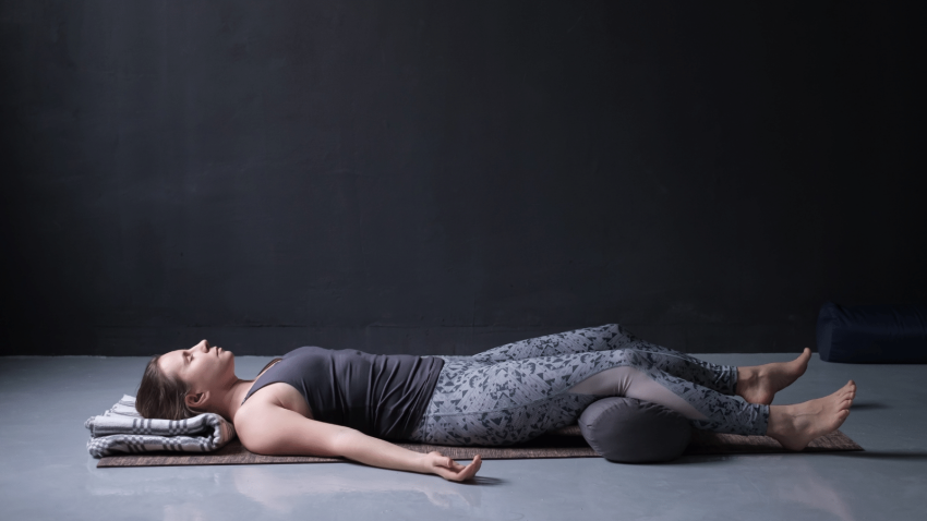 Savasana pictured here with blankets and bolster for greater comfort, to ease psoas muscle pain