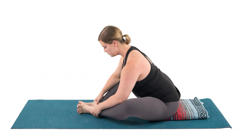 Woman practicing bound angle yoga pose to relieve high blood pressure