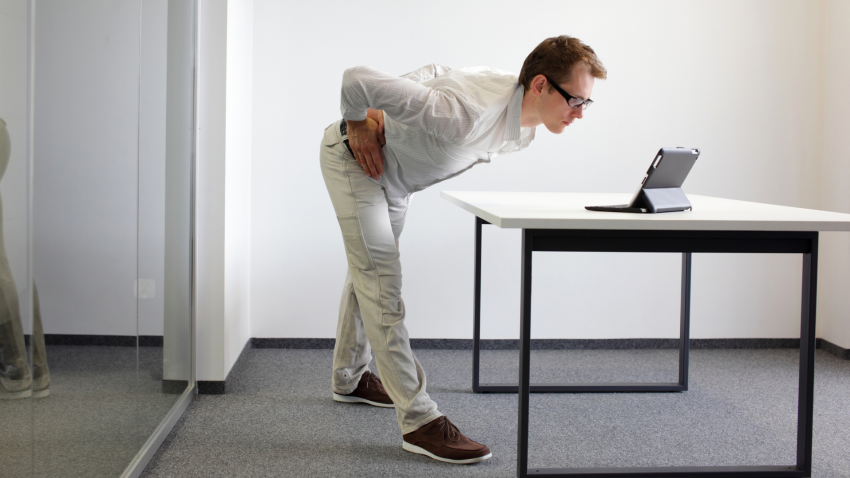Man performing easy yoga back stretch in workplace