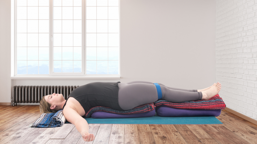 Woman practicing yoga restorative supported backbend. Woman practicing yoga restorative supported backbend.