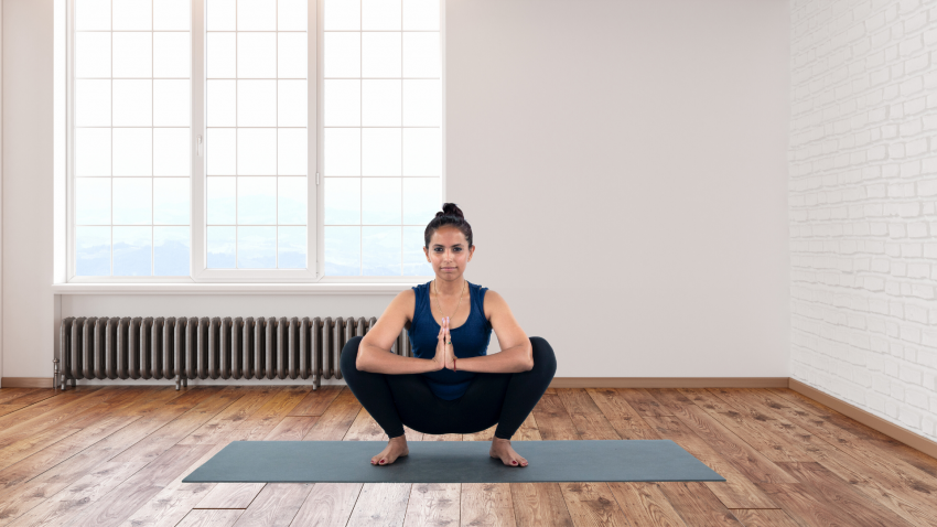 Woman practicing yoga for flat feet Garland Pose (Malasana)