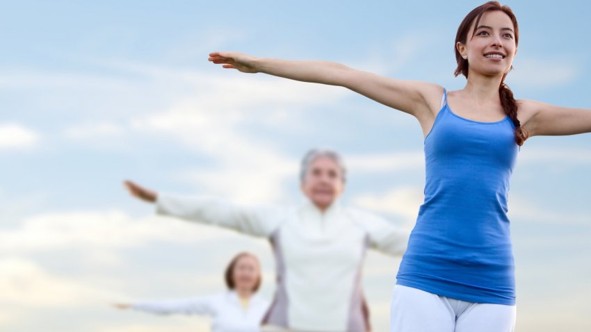 Women practicing yoga together, in Mountain Pose (Tadasana) with arms wide