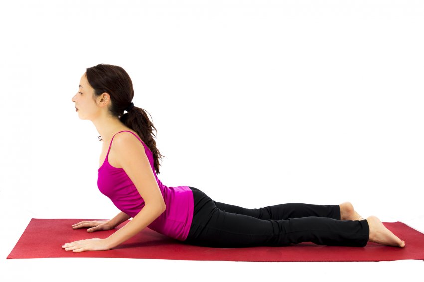 Woman in Cobra Pose (Bhujangasana) practicing beginning yoga Woman in Cobra Pose (Bhujangasana) practicing beginning yoga