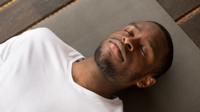 Yoga man lying down in savasana 