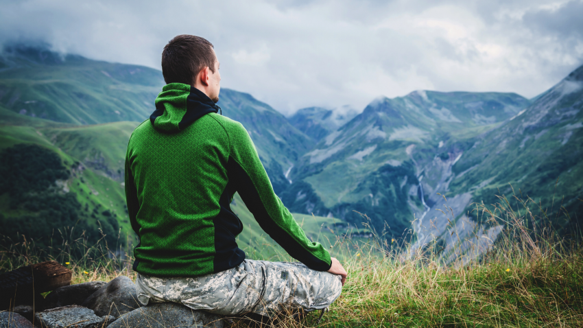 veteran yoga man meditating outside in mountains