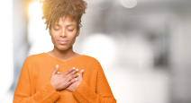 Beautiful young african american woman smiling with hands on chest with closed eyes and grateful ges