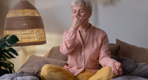 Senior woman practicing yoga at home, making Alternate Nostril Breathing or nadi shodhana