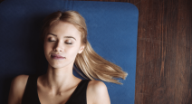 Top view of cute young fitness woman lying on the floor on mat with eyes closed.