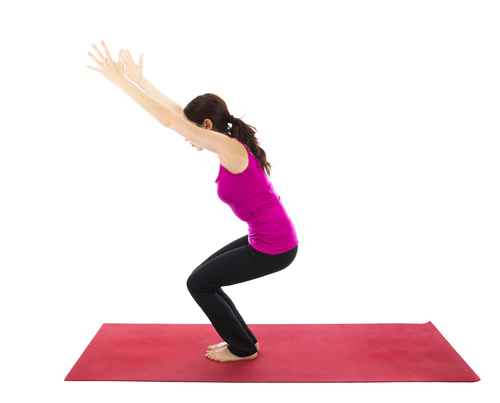 Woman practicing alternative to Pigeon Pose, in Utkatasana (Fierce yoga Pose) to stabilize the hips